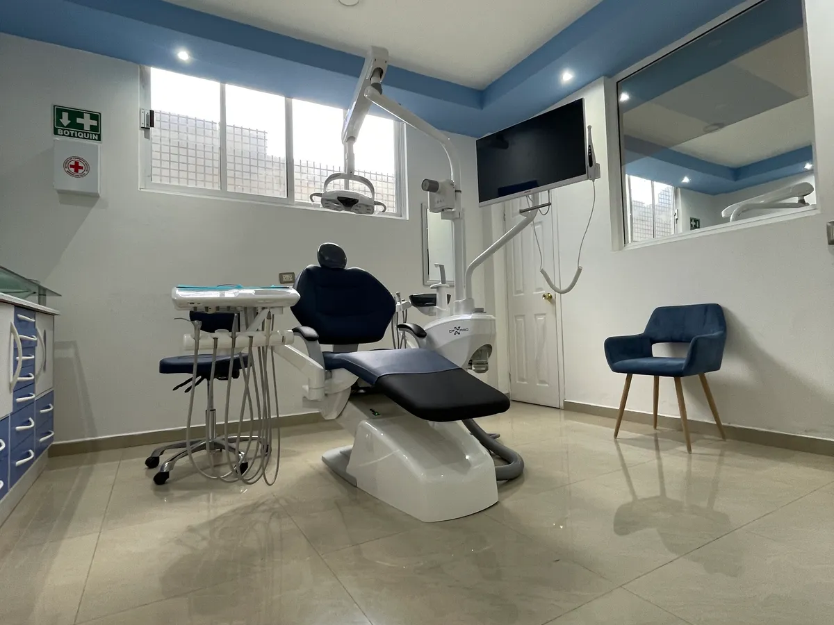 Sala de atención con sillón dental, pantalla en la pared y silla para acompañante
