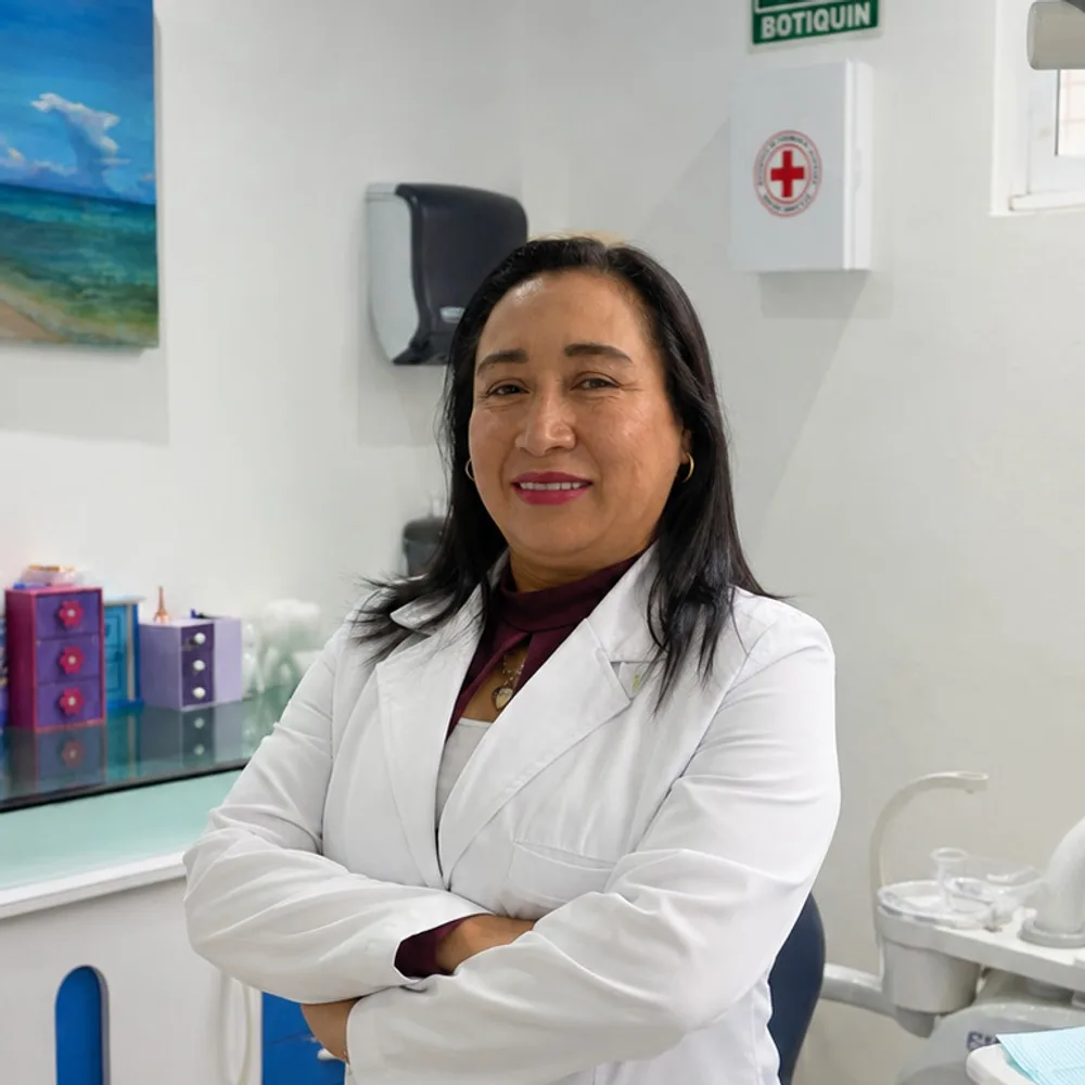 La Dra. Gloria Portillo Atempa, con bata blanca, junto a la unidad dental de su consultorio